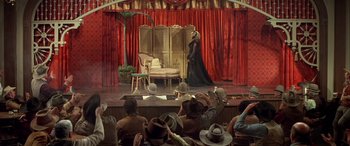Movie still from “Blazing Saddles” (1974), directed by Mel Brooks – A woman in a long black dress on a stage; Wide shot, High angle