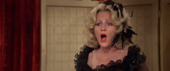 Movie still from “Blazing Saddles” (1974), directed by Mel Brooks – A woman in a black and white dress with red lipstick; Close Up shot, High angle