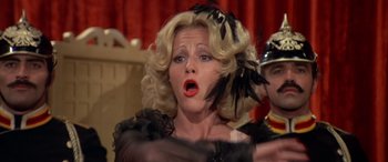 Movie still from “Blazing Saddles” (1974), directed by Mel Brooks – A woman in a black dress and a black feather hat; Close Up shot, Low angle