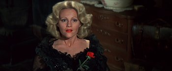 Movie still from “Blazing Saddles” (1974), directed by Mel Brooks – A woman with blonde hair wearing a black dress and holding a red rose; Close Up shot, High angle