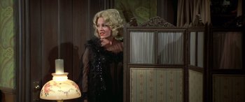 Movie still from “Blazing Saddles” (1974), directed by Mel Brooks – A woman with blonde hair wearing a black dress; Medium shot, Over the shoulder angle