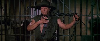 Movie still from “Blazing Saddles” (1974), directed by Mel Brooks – A man with a chain around his neck; Medium shot, Low angle