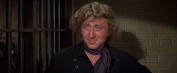 Movie still from “Blazing Saddles” (1974), directed by Mel Brooks – A person with curly hair wearing a black jacket; Close Up shot, Over the shoulder angle