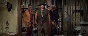 Movie still from “Blazing Saddles” (1974), directed by Mel Brooks – A group of men standing next to each other in a jail cell; Wide shot, Over the shoulder angle