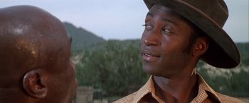Movie still from “Blazing Saddles” (1974), directed by Mel Brooks – A black man wearing a cowboy hat looking up at the sky; Close Up shot, Over the shoulder angle