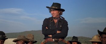 Movie still from “Blazing Saddles” (1974), directed by Mel Brooks – A man in a cowboy hat is sitting on top of a horse; Close Up shot, Low angle