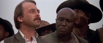 Movie still from “Blazing Saddles” (1974), directed by Mel Brooks – A man and a man in a crowd of people; Close Up shot, Low angle