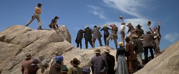 Movie still from “Blazing Saddles” (1974), directed by Mel Brooks – A group of people standing on top of a rock formation; Wide shot, Low angle