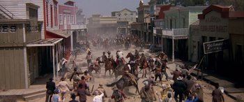 Movie still from “Blazing Saddles” (1974), directed by Mel Brooks – A crowd of people riding horses down a dirt road; Extreme Wide shot, High angle