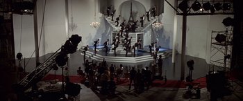 Movie still from “Blazing Saddles” (1974), directed by Mel Brooks – A group of men in black suits are standing in front of a staircase; Extreme Wide shot, High angle