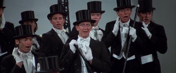 Movie still from “Blazing Saddles” (1974), directed by Mel Brooks – A group of men in top hats and white gloves; Medium shot, Low angle