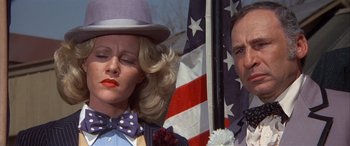 Movie still from “Blazing Saddles” (1974), directed by Mel Brooks – A man and a woman standing in front of an american flag; Close Up shot, Low angle