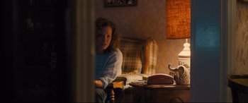 Movie still from “Bleed for This” (2016), directed by Ben Younger – A woman sitting on a chair in a living room; Medium shot, Over the shoulder angle
