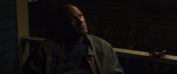 Movie still from “Bleed for This” (2016), directed by Ben Younger – A bald man wearing a leather jacket looking off into the distance; Close Up shot, Over the shoulder angle