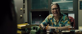 Movie still from “Bleed for This” (2016), directed by Ben Younger – An older man sitting at a table with a lot of pencils; Medium shot, Over the shoulder angle