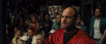 Movie still from “Bleed for This” (2016), directed by Ben Younger – A crowd of people watching a man in a red robe; Close Up shot, Over the shoulder angle