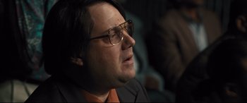 Movie still from “Bleed for This” (2016), directed by Ben Younger – A person wearing glasses and a suit; Close Up shot, Over the shoulder angle