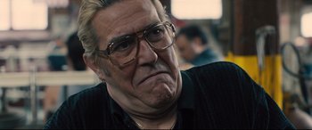 Movie still from “Bleed for This” (2016), directed by Ben Younger – An older man wearing glasses and a black shirt; Close Up shot, Over the shoulder angle
