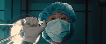 Movie still from “Bleed for This” (2016), directed by Ben Younger – A woman wearing a surgical mask and a surgical cap; Close Up shot, Low angle