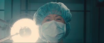 Movie still from “Bleed for This” (2016), directed by Ben Younger – A woman wearing a surgical mask and a surgical cap; Close Up shot, Low angle