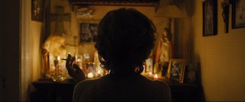 Movie still from “Bleed for This” (2016), directed by Ben Younger – A woman sitting in front of a candle lit fireplace; Medium shot, Over the shoulder angle