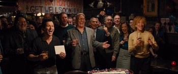 Movie still from “Bleed for This” (2016), directed by Ben Younger – A group of people standing around a birthday cake; Wide shot, High angle
