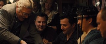 Movie still from “Bleed for This” (2016), directed by Ben Younger – Two men sitting next to each other at a party; Medium shot, Over the shoulder angle