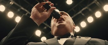 Movie still from “Bleed for This” (2016), directed by Ben Younger – A person holding a microphone up to their mouth; Extreme Close Up shot, Low angle