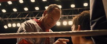Movie still from “Bleed for This” (2016), directed by Ben Younger – A man in a boxing ring pointing at something on the ground; Close Up shot, Over the shoulder angle