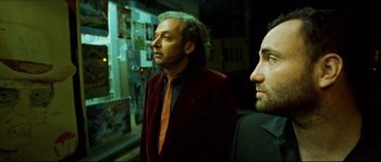 Movie still from “Bleeder” (1999), directed by Nicolas Winding Refn – A man in a red jacket standing next to another man in a black shirt; Close Up shot, Low angle