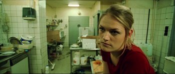 Movie still from “Bleeder” (1999), directed by Nicolas Winding Refn – A woman standing in a room with a lot of trash around her; Close Up shot, Low angle