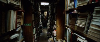 Movie still from “Bleeder” (1999), directed by Nicolas Winding Refn – A room filled with lots and lots of books on the shelves; Wide shot, Overhead angle