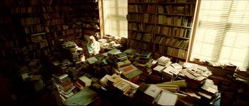 Movie still from “Bleeder” (1999), directed by Nicolas Winding Refn – A person sitting in front of a large pile of books; Wide shot, High angle