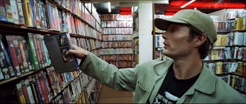 Movie still from “Bleeder” (1999), directed by Nicolas Winding Refn – A man is reaching for a dvd in a video store; Medium shot, High angle