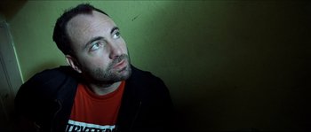Movie still from “Bleeder” (1999), directed by Nicolas Winding Refn – A person wearing a red shirt; Close Up shot, Low angle