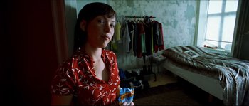 Movie still from “Bleeder” (1999), directed by Nicolas Winding Refn – A woman in a red shirt is holding a box of cereal; Medium shot, Over the shoulder angle