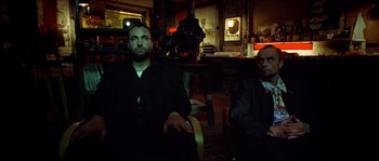 Movie still from “Bleeder” (1999), directed by Nicolas Winding Refn – Two men are sitting in a dark room; Medium shot, Low angle