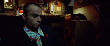 Movie still from “Bleeder” (1999), directed by Nicolas Winding Refn – A man sitting in front of a wall in a room; Close Up shot, Low angle