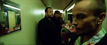 Movie still from “Bleeder” (1999), directed by Nicolas Winding Refn – A group of men standing next to each other in a room; Medium shot, Over the shoulder angle