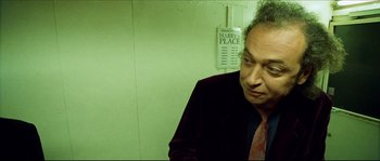 Movie still from “Bleeder” (1999), directed by Nicolas Winding Refn – A man in a black jacket and a red tie; Medium shot, High angle