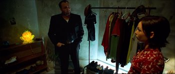 Movie still from “Bleeder” (1999), directed by Nicolas Winding Refn – A man standing in a dark room next to clothes; Medium shot, Low angle