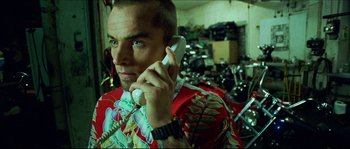 Movie still from “Bleeder” (1999), directed by Nicolas Winding Refn – A man wearing a hawaiian shirt talking on a phone; Close Up shot, Low angle