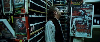 Movie still from “Bleeder” (1999), directed by Nicolas Winding Refn – A man standing in front of a wall of books; Medium shot, Low angle