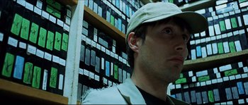 Movie still from “Bleeder” (1999), directed by Nicolas Winding Refn – A person wearing a hat in front of a shelf; Close Up shot, Low angle