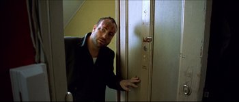 Movie still from “Bleeder” (1999), directed by Nicolas Winding Refn – A man in a black jacket leaning against a door; Medium shot, Low angle