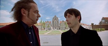 Movie still from “Bleeder” (1999), directed by Nicolas Winding Refn – Two men standing in front of a building; Close Up shot, Low angle