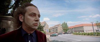 Movie still from “Bleeder” (1999), directed by Nicolas Winding Refn – A man standing on the side of a road near cars; Close Up shot, Low angle