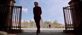 Movie still from “Bleeder” (1999), directed by Nicolas Winding Refn – A man walking down the street in a red suit; Wide shot, Low angle
