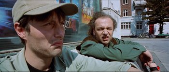 Movie still from “Bleeder” (1999), directed by Nicolas Winding Refn – Two men sitting next to each other in front of a movie poster; Close Up shot, Low angle