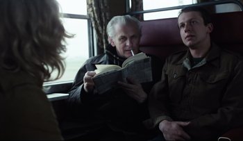 Movie still from “Blind Chance” (1987), directed by Krzysztof Kieslowski – A man sitting next to another man reading a book; Medium shot, Over the shoulder angle